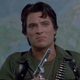 A man standing in front of a world map dressed in military fatigues and holding a gun looks angry in a scene from Day of the Dead.